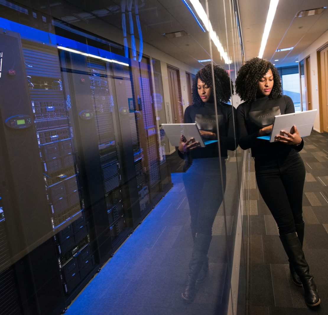 IT professional using a tablet beside server racks in a secure data center.
