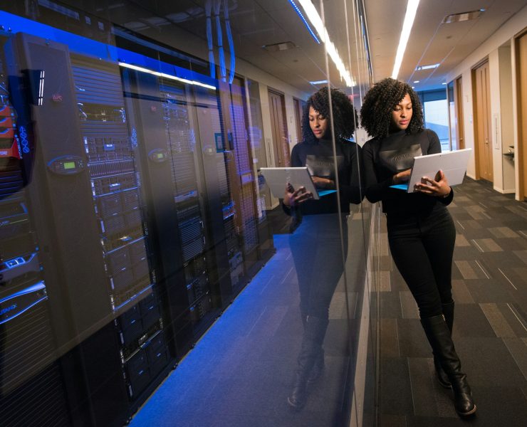 IT professional using a tablet beside server racks in a secure data center.