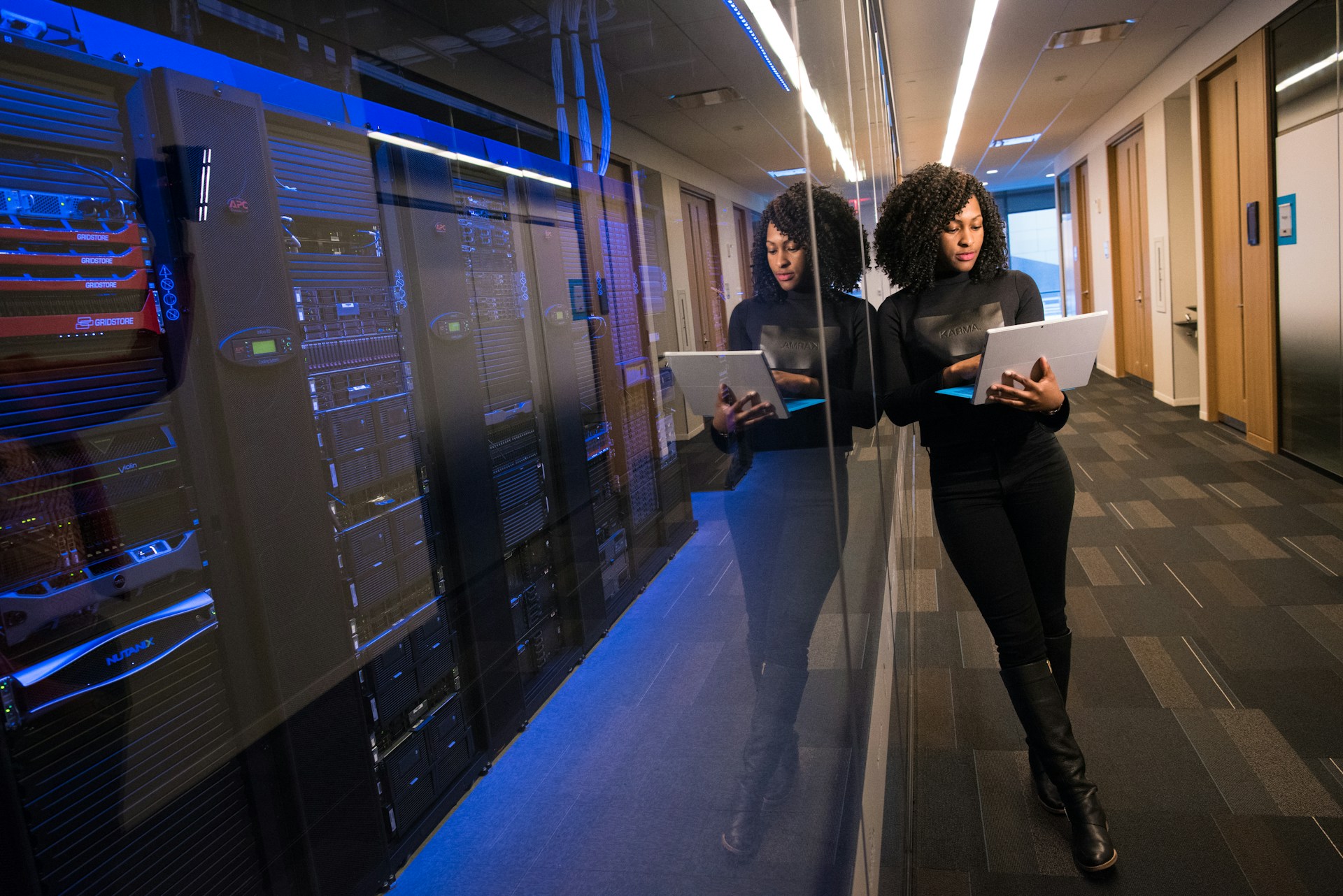 IT professional using a tablet beside server racks in a secure data center.